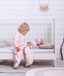 Toddler sitting on bed wearing Sleep Suit Sack Petals