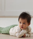 Infant crawling on it's stomach wearing ergoPouch Sleeping Sack with the added layer of Arm Warmers