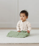 Infant sitting up wearing ergoPouch Sleeping Sack with the added layer of Arm Warmers