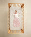 Baby in crib wearing ergoPouch Sleep Suit Sack 1.0 TOG Daisies with the added layer of Arm Warmers Oatmeal Marle