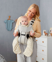 Parent holing a baby in a carrier wearing an ergoPouch Sleep Suit Sack 3.5 TOG Night Sky