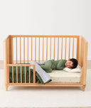 Toddler lying in crib on a ergoPouch Organic Toddler Pillow and Case Caramel Grid, designed to support the correct alignment of the neck during sleep