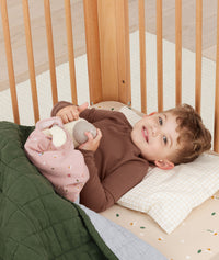 Toddler lying in crib on a ergoPouch Organic Toddler Pillow and Case Caramel Grid, designed to support the correct alignment of the neck during sleep