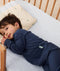 Toddler lying in crib on a ergoPouch Organic Toddler Pillow and Case Daisy Sprinkle, designed to support the correct alignment of the neck during sleep