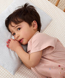 Toddler lying in crib on a ergoPouch Organic Toddler Pillow and Case Midnight Stripe, designed to support the correct alignment of the neck during sleep