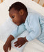 Toddler lying in crib on a ergoPouch Organic Toddler Pillow and Case Midnight Stripe, designed to support the correct alignment of the neck during sleep