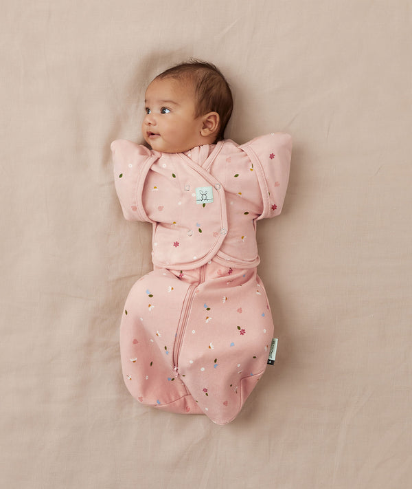 Newborn being swaddled in ergoPouch Cocoon Swaddle Sack 1.0 TOG with Butterfly Cardi for arms up sleeping, in heritage color Daisies