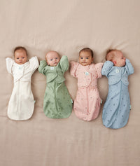 Four newborns being swaddled in ergoPouch Cocoon Swaddle Sack 0.2 TOG with Butterfly Cardi for arms up sleeping, in heritage colors Willow, Daisies, Dragonflies and Oatmeal Marle 