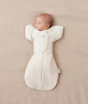 Newborn being swaddled in ergoPouch Cocoon Swaddle Sack 1.0 TOG Oatmeal Marle with Butterfly Cardi Oatmeal Marle for arms up sleeping