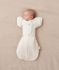 Newborn being swaddled in ergoPouch Cocoon Swaddle Sack 1.0 TOG Oatmeal Marle with Butterfly Cardi Oatmeal Marle for arms up sleeping
