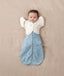A newborn baby in a Cocoon Swaddle Sack 1.0 TOG Dragonflies with the arms up transition using a Butterfly Cardi Oatmeal Marle