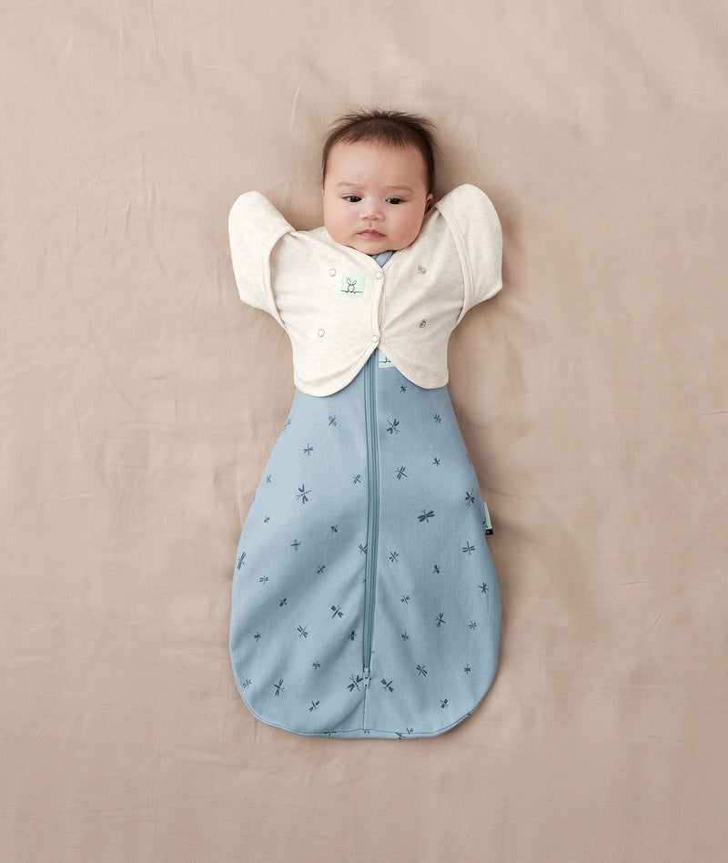 A newborn baby in a Cocoon Swaddle Sack 1.0 TOG Dragonflies with the arms up transition using a Butterfly Cardi Oatmeal Marle