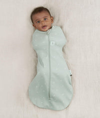 Newborn wearing an ergoPouch Cocoon Swaddle Sack 0.2 TOG Sage with arms in