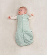 Baby being swaddled in ergoPouch Cocoon Swaddle Sack in Sage, arms out transition