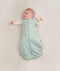 Baby being swaddled in ergoPouch Cocoon Swaddle Sack in Sage, arms out transition