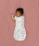 Newborn transitioning to arms-out sleeping, in an ergoPouch Cocoon Swaddle Sack 1.0 TOG Daydream