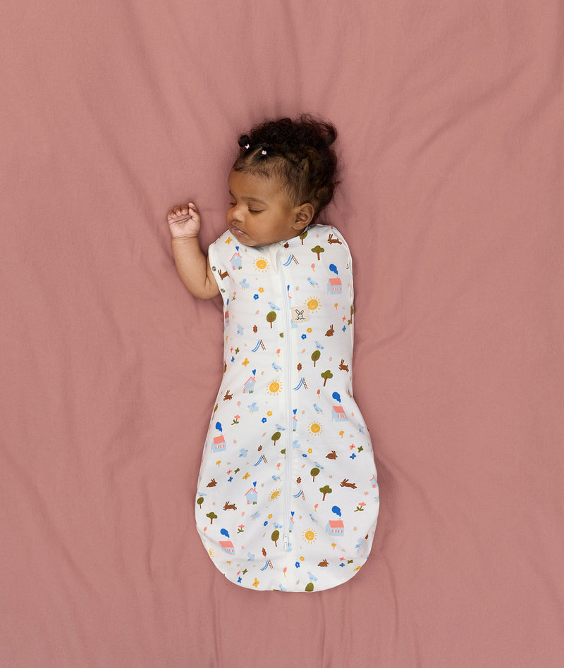 Newborn transitioning to arms-out sleeping, in an ergoPouch Cocoon Swaddle Sack 1.0 TOG Daydream
