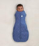 Newborn wearing an ergoPouch Cocoon Swaddle Sack 0.2 TOG Night Sky with arms in