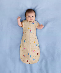 Baby sleeping with arms out in a ergoPouch Cocoon Swaddle Sack 1.0 TOG Birthday Blobs