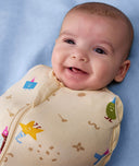 Smiling newborn swaddled in an ergoPouch Cocoon Swaddle Sack 1.0 TOG Birthday Blobs