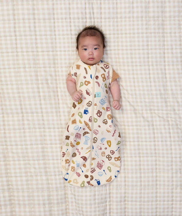 Newborn baby wearing ergoPouch Cocoon Swaddle Sack 0.2 TOG in Bon Appetit with both arms out