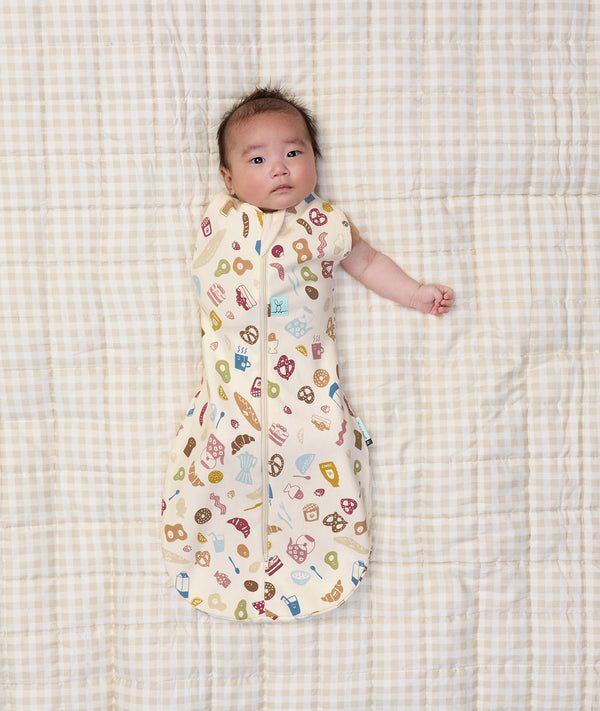 Newborn baby wearing ergoPouch Cocoon Swaddle Sack 0.2 TOG in Bon Appetit with one arm out