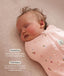 Close up of a newborn being swaddled in ergoPouch Cocoon Swaddle Sack 1.0 TOG Daisies with text highlighting swaddling benefit and TOG rating feature.