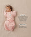 Baby lying on a beige surface in a pink floral swaddle paired with a 