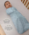 Baby wrapped in a blue Cocoon Swaddle Sack lying in a crib with text highlighting swaddling benefit and TOG rating feature.