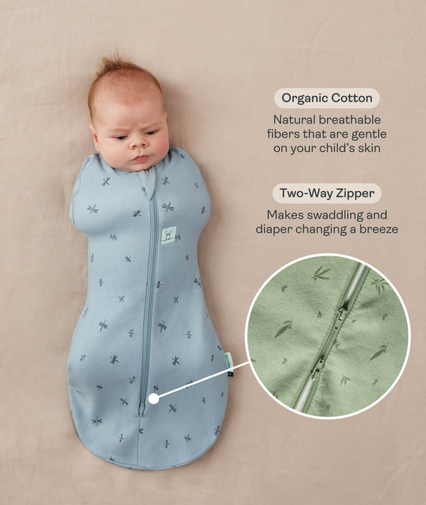 Newborn baby lying on a beige surface being swaddled in ergoPouch Cocoon Saddle Sack Dragonflies with text highlighting organic cotton and two-way zipper and a close-up image of the dual zippers.