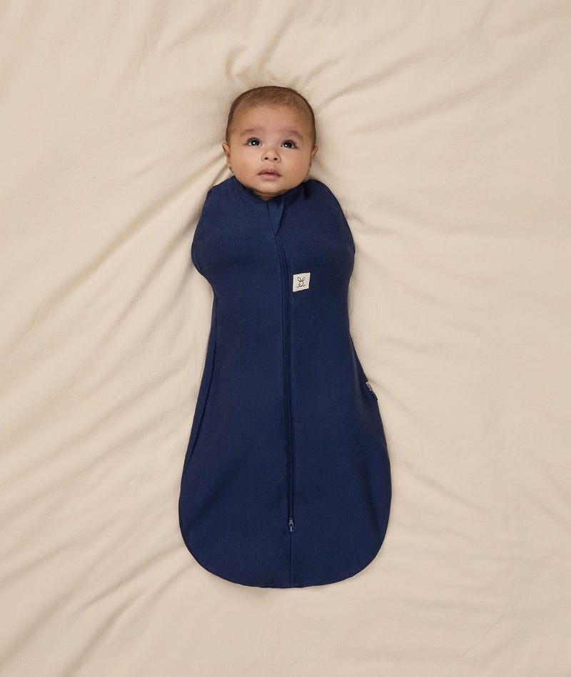 Baby snuggled in ergoPouch Cocoon Swaddle Sack with its arms in.