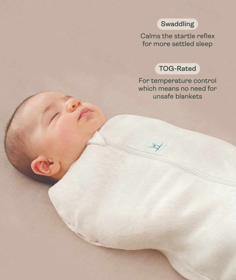 Close-up view of a sleeping baby being swaddled in an ergoPouch Cocoon Swaddle Sack Oatmeal Marle with text highlighting swaddling benefit and TOG rating feature.