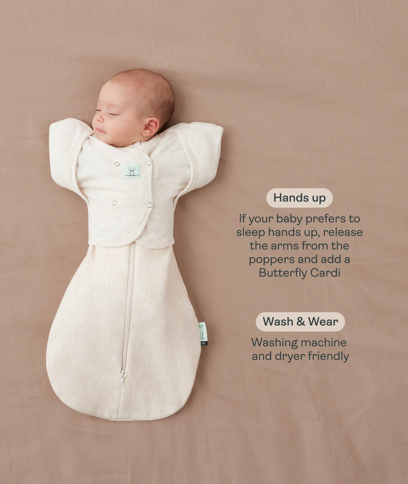 Baby lying on a beige surface in an oatmeal-colored swaddle sack paired with a 