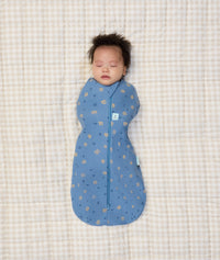 Newborn asleep on a crib wearing ergoPouch Cocoon Swaddle Sack 1.0 TOG in Petite Pretzel