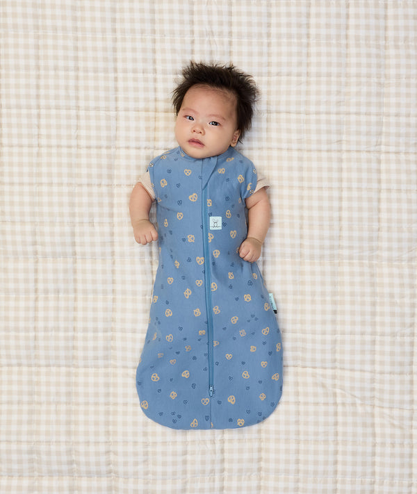 Newborn baby wearing ergoPouch Cocoon Swaddle Sack 0.2 TOG in Petit Pretzel with both arms out