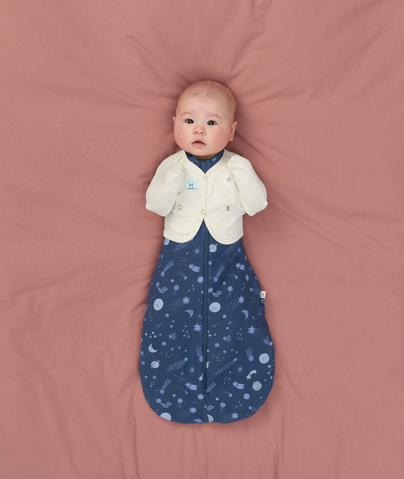 Newborn using Butterfly Cardi Oamteal Marle for arms up sleeping, wearing a ergoPouch Cocoon Swaddle Sack 1.0 TOG Starbeam underneath
