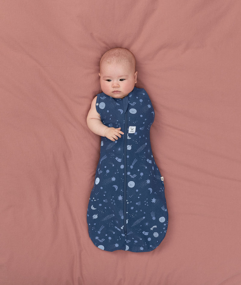Baby transitioning to arms out sleeping easily with the ergoPouch Cocoon Swaddle Sack 1.0 TOG Starbeam