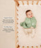 Baby lying in a wooden crib wearing a sage green patterned swaddle sack over footed pajamas, with product feature text callouts highlighting organic cotton fabric and two-way zipper features.