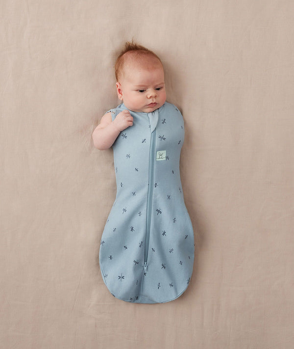 Newborn wearing ergoPouch Cocoon Swaddle Sack 0.2 TOG Dragonflies, transitioning to arms out sleeping