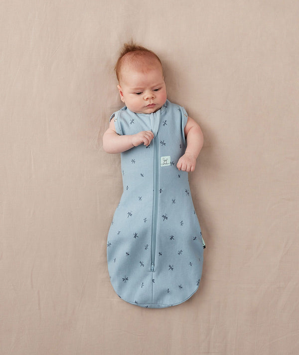 Newborn wearing ergoPouch Cocoon Swaddle Sack 0.2 TOG Dragonflies, transitioning to arms out sleeping
