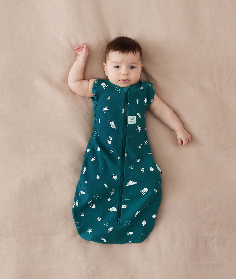 Baby sleeping with arms out in a ergoPouch Cocoon Swaddle Sack 0.2 TOG Ocean Blue