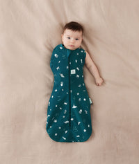 Baby wearing a ergoPouch Cocoon Swaddle Sack 0.2 TOG Ocean Blue, transitioning to arms out sleeping