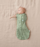 Baby wearing a ergoPouch Cocoon Swaddle Sack 0.2 TOG Willow, transitioning to arms out sleeping