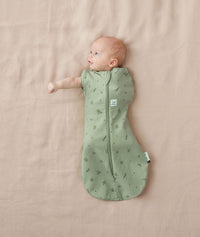Baby wearing a ergoPouch Cocoon Swaddle Sack 1.0 TOG Willow, transitioning to arms out sleeping
