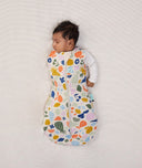 Newborn wearing ergoPouch Cocoon Swaddle Sack 2.5 TOG Fruit Salad, transitioning to arms out sleeping