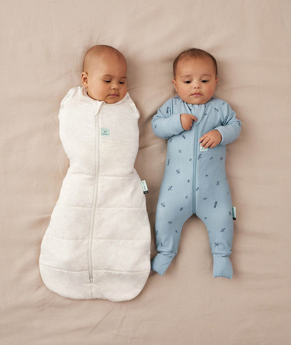 Two babies asleep in ergoPouch Cocoon Swaddle Sack 2.5 TOG Oatmeal Marle and Long Sleeve Romper