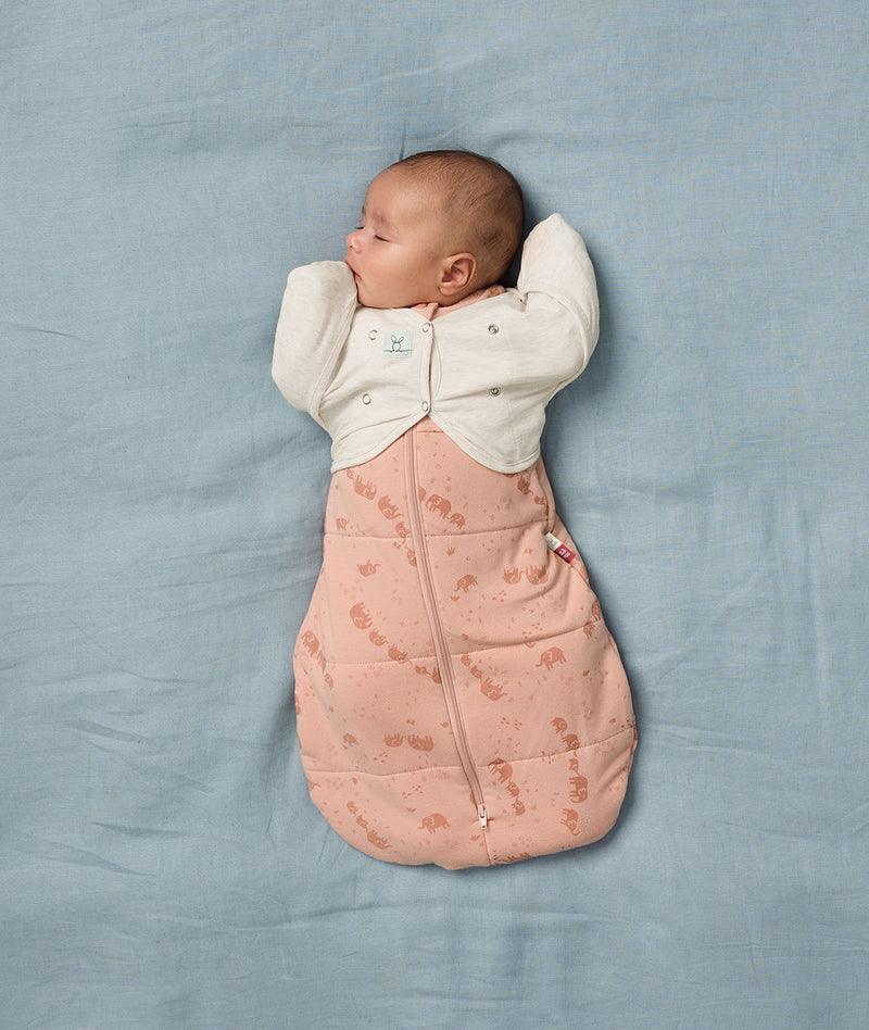 Newborn being swaddled in an ergoPouch Cocoon Swaddle Sack 2.5 TOG Elephant Parade with a Butterfly Cardi Oatmeal Marle over the top, for arms up sleeping