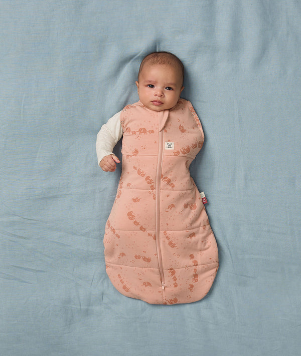 Newborn transitioning to arms out sleeping in an ergoPouch Cocoon Swaddle Sack 3.5 TOG Elephant Parade, perfect for winter