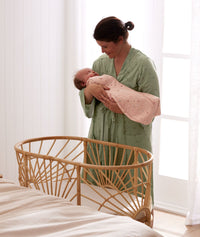 Baby swaddled by mothers wearing a ergoPouch Cocoon Swaddle Sack 1.0 TOG Daisies