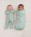 Babies lying in ergoPouch Long Sleeve Romper in Sage and Cocoon Swaddle Bag in Sage